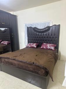 a large bed with a black headboard and red pillows at مطل محنا الجبلي in Ajloun