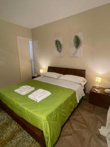 a bedroom with a green bed with two towels on it at La casa al mare in Palermo