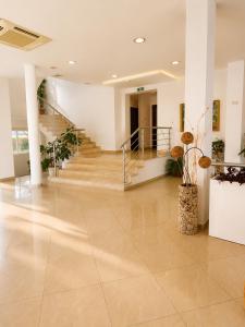a lobby with a staircase and a hallway with potted plants at Hotel Jasmine in Byala +11 photos