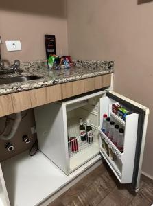 a small kitchen with a counter and an open refrigerator at Flat no centro de Curitiba in Curitiba