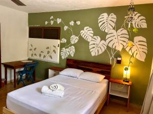 a bedroom with a white bed with a green wall at Casa Samay in Cozumel