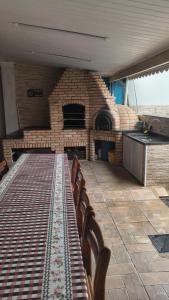 a kitchen with a table with a brick oven at Linda casa Edícula "fundos do terreno" com piscina in Itanhaém
