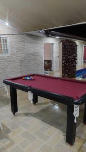 a red pool table in a room with a fireplace at Linda casa Edícula "fundos do terreno" com piscina in Itanhaém