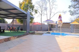 a patio with an umbrella and a table and chairs at Viva Guest House in Trevallyn