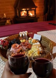 a tray of food on a table with two glasses at Chales Estância Verdejante in Sapucaí-Mirim