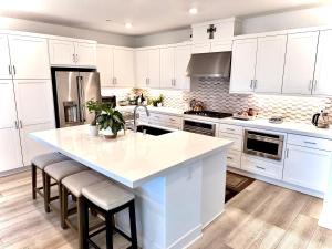 a kitchen with white cabinets and a large island with stools at Valencia Resort in Santa Clarita