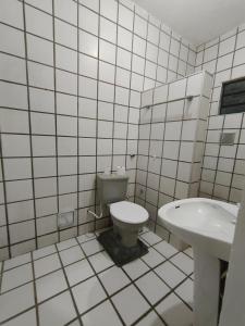 a white tiled bathroom with a toilet and a sink at Pousada Bom Jesuss in Juazeiro do Norte