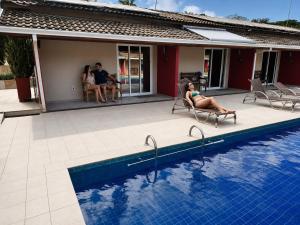 a woman sitting in a chair next to a swimming pool at Hotel Pousada Villa Itália Olímpia in Olímpia +119 photos