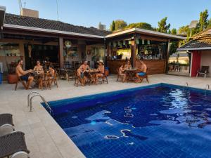 a group of people sitting at tables by a pool at Hotel Pousada Villa Itália Olímpia in Olímpia