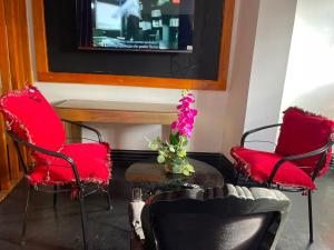 two red chairs and a table with a vase of flowers at Hotel Cristian in Puyo
