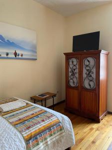 a bedroom with a bed and a wooden cabinet with a television at Mía Leticia B&B in Quito