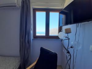 a bedroom with a window and a bed and a chair at Symbligates rocks in Kalymnos