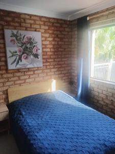 a bedroom with a blue bed with a brick wall at Connies Retreat in Gold Coast