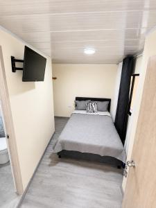 a bedroom with a bed and a flat screen tv at Hotel Casa Mónaco Tunja in Tunja
