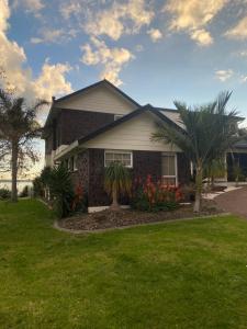 a house with palm trees and flowers in the yard at Wattle Downs Palm Beach Studio in Auckland