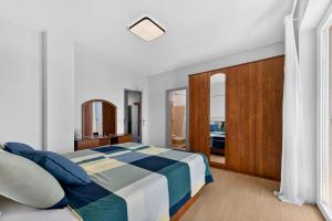 a white bedroom with a bed and a wooden cabinet at Room Blue View in Mlini