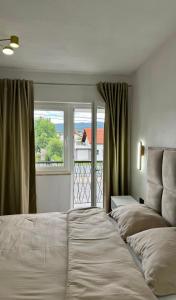 a bedroom with two beds in front of a window at Apartmani SARA Bugojno in Bugojno