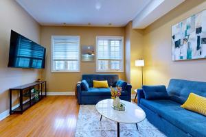a living room with two blue couches and a tv at Private Rooftop Group Suite near Oriole Park - Eglinton Hotel in Toronto