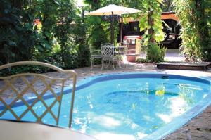 a small swimming pool with a table and an umbrella at Hotel La Hacienda in Tuxtla Gutiérrez