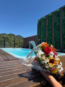 a person holding a bouquet of flowers next to a swimming pool at Pousada do Francês in Ubatuba