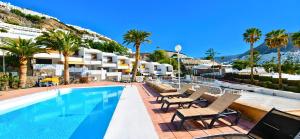 a hotel swimming pool with chairs and palm trees at Apartamentos Panamá in Puerto Rico de Gran Canaria
