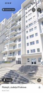 a large white building with stairs in front of it at Apartament White Tower in Ploieşti