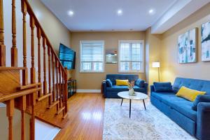 a living room with blue couches and a staircase at Private Rooftop Group Suite near Oriole Park - Eglinton Hotel in Toronto