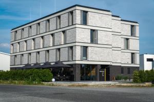a tall brick building with an umbrella in front of it at Hotel DEJANIL Hannover Burgdorf in Burgdorf