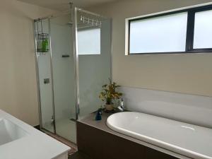 a bathroom with a shower and a tub and a sink at Enkindled Haven in Moonah