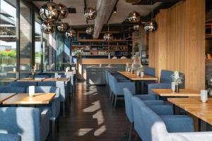 a restaurant with wooden tables and blue chairs at Hotel DEJANIL Hannover Burgdorf in Burgdorf