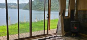 a room with a fireplace and a view of the water at Casa primera linea de playa in Maricó +11 photos
