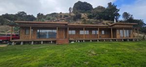 a large wooden house on a grassy field at Casa primera linea de playa in Maricó