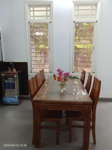a dining room table with a vase of flowers on it at Lockhang homestay in Thanh Ðông (1)