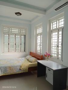 a bedroom with a bed and a desk and windows at Lockhang homestay in Thanh Ðông (1)