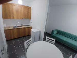 a kitchen with a green couch and a table and chairs at Enes apartament in Krujë