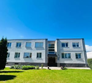 a building with a grassy yard in front of it at Levandų šeimyniniai apartamentai su vonia ir sodu in Ryškėnai
