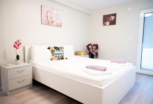 a large white bed in a white room with flowers at Villa Aki in Posedarje