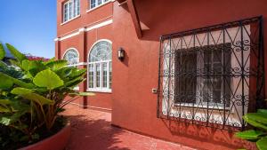 a red building with a door with a gate at Vila Olivença in Costa da Caparica