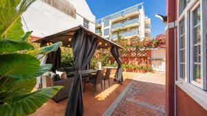 a patio with a table and chairs under an umbrella at Vila Olivença in Costa da Caparica