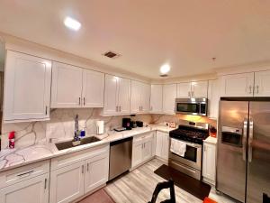 a kitchen with white cabinets and stainless steel appliances at The Elegant Suite - 2BR with Great Amenities in Paterson