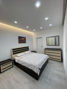 a bedroom with a large bed and two drawers at Paco Apartment Center Shkoder in Shkodër