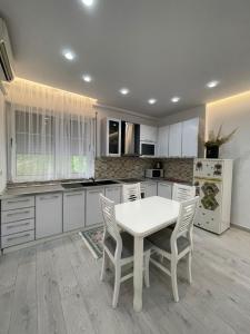 a kitchen with a white table and white cabinets at Paco Apartment Center Shkoder in Shkodër