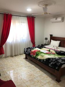 a bedroom with a bed and a window with red curtains at Abronoma Guest House in Ogbojo +39 photos