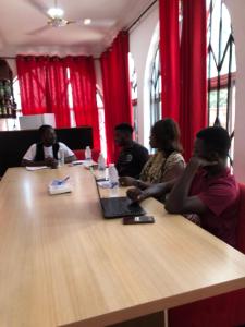 a group of people sitting at a table with a laptop at Abronoma Guest House in Ogbojo