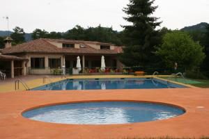 a large swimming pool in front of a house at Camping Vidrà in Vidrá