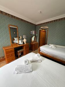 a bedroom with two beds and a dresser and a mirror at Imperial Lodge in Lisdoonvarna