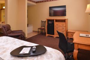 ein Hotelzimmer mit einem Bett, einem Schreibtisch und einem TV in der Unterkunft Country Hearth Inn & Suites Edwardsville in Edwardsville