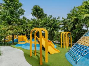 a playground with yellow and blue slides on the grass at Pullman Khao Lak Resort in Khao Lak