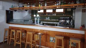 a bar with a row of wooden bar stools at Camping Vidrà in Vidrá