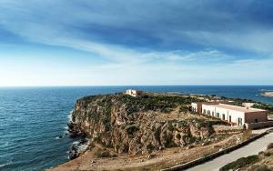 a building on a cliff next to the ocean at Nido Del Pellegrino in Favignana